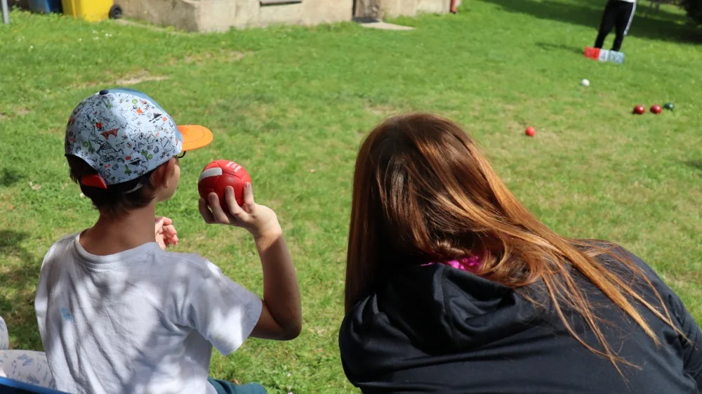 Boccia hraná venku na trávě – hráč drží červený míč